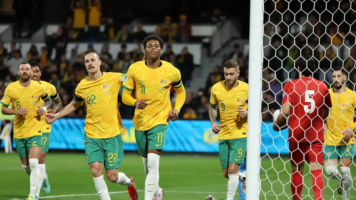 Players celebrating in yellow kits during an international match